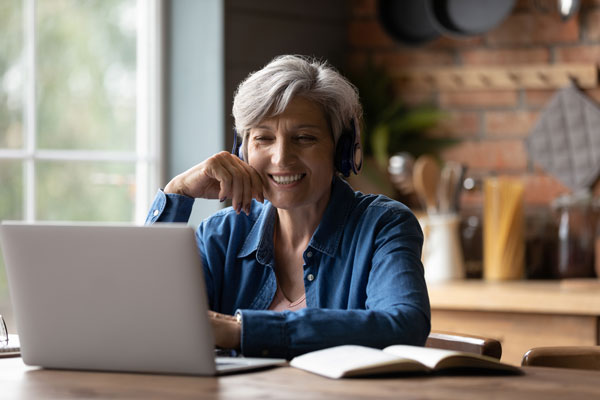 an older woman smiling at a laptop